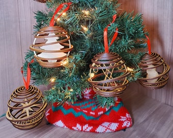 May include: Six wooden Christmas ornaments with intricate laser-cut designs, including a tree, angel, and star, hanging on a green artificial Christmas tree with white lights.