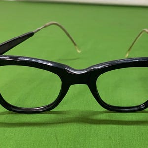 May include: Black plastic framed glasses with a cat-eye shape and thin metal arms.