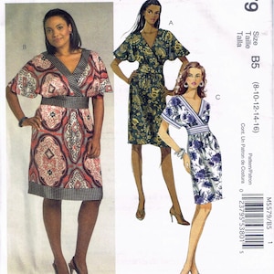 May include: McCall's sewing pattern M5579 featuring three dress designs. The pattern includes sizes B5 (8-10-12-14-16). The dresses have a wrap-style design with various sleeve lengths and prints.