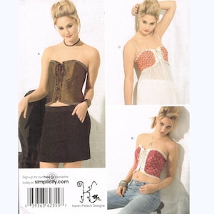 May include: Simplicity sewing pattern 2355 featuring three different corset and top designs. The pattern includes sizes 14, 16, 18, and 20. The image shows a woman wearing each of the designs.