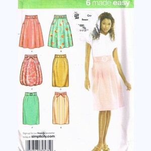May include: Simplicity pattern 3792 for six skirt styles, sizes P5 (12, 14, 16, 18, 20). The image shows a woman wearing a pink skirt. The pattern includes the text "6 made easy" and the Simplicity logo. Measurements are in cm.