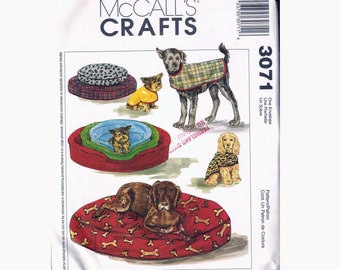 May include: McCall's Crafts sewing pattern number 3071 for dog beds and coats. The pattern includes three different dog bed designs and three different dog coat designs. The dog beds are shown in red, green, and brown with various patterns. The dog coats are shown in plaid, leopard print, and a yellow solid color.