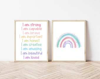May include: Two framed art prints. One features a rainbow with pastel colors. The other print has the words "I am strong, capable, brave, important, honest, creative, amazing, beautiful, loved" in a rainbow of colors. Both prints have a white background.