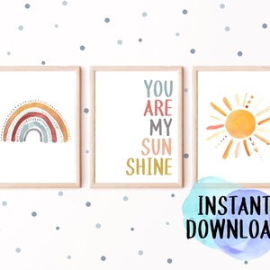 May include: Three framed watercolor art prints. The prints feature a rainbow, the phrase "You Are My Sunshine," and a sun. The art is in soft, warm colors, perfect for a nursery or child's room. The words "Instant Download" are also visible.