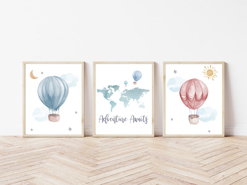 May include: Three framed watercolor prints featuring hot air balloons, clouds, stars, and a sun. One print has a blue balloon, another a world map with balloons, and the third a pink balloon. The text "Adventure Awaits" is on one print.