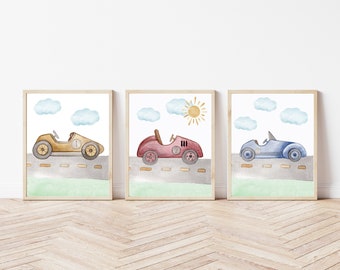 May include: Set of three framed watercolor prints featuring vintage race cars in gold, red, and blue. Each car is on a gray road with a green grassy area, blue clouds, and a yellow sun.