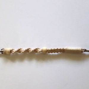 May include: A beige macrame keychain with two wooden beads and silver metal clasps.