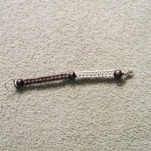 May include: A brown and white braided bracelet with a silver clasp and brown beads.