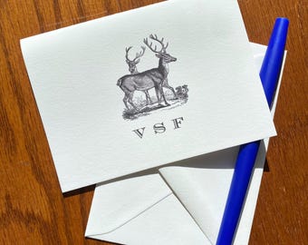 May include: A white card with a black and white illustration of two deer with antlers. The card has the initials "VSF" printed in black.