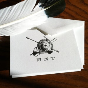 May include: A white card with a black and white illustration of a horse's head with a whip and horn. The text "HNT" is printed below the illustration.
