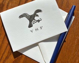 May include: A white card with a black and white illustration of an eagle with a snake in its talons. The letters "VSF" are printed below the image.