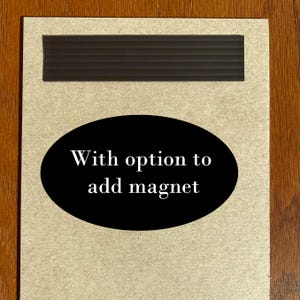 May include: A brown cardboard sign with a black oval sticker that says "With option to add magnet".