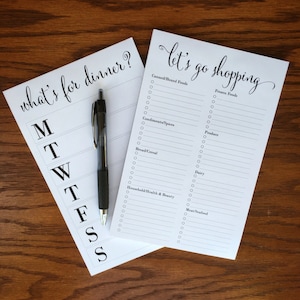 May include: Two white notepad lists with black text. The top list says "what's for dinner?" with days of the week listed below. The bottom list says "Let's go shopping" with categories for grocery shopping listed below.
