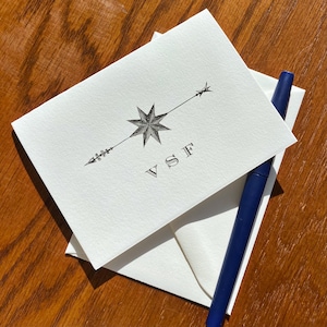 May include: A white card with a black and white illustration of a star with an arrow pointing to the right. The initials "VSF" are printed below the star.