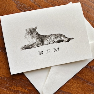 May include: Ivory stationery set featuring a detailed black and white illustration of a tiger in a reclining pose. The initials "RFM" are printed below the tiger. Includes a matching envelope.