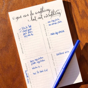 May include: A white notepad with a blue pen on top. The notepad has a grid pattern and is divided into four sections. Each section has a heading: "Important/Urgent", "Important/Not Urgent", "Not Important/Urgent", and "Not Important/Not Urgent". The notepad has the text "You can do anything, but not everything" written at the top. The notepad has a list of tasks written in blue ink.