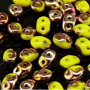 May include: Close-up of a collection of yellow and gold beads. The beads have a glossy finish and are scattered across a dark surface. The beads are a mix of shapes, including round and oval.
