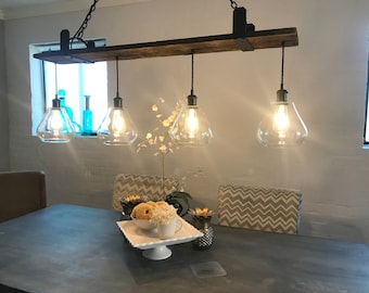 May include: A rustic wooden chandelier with four clear glass globe light fixtures hanging from black cords. The chandelier is mounted on a wooden beam and is illuminated with warm white light bulbs.