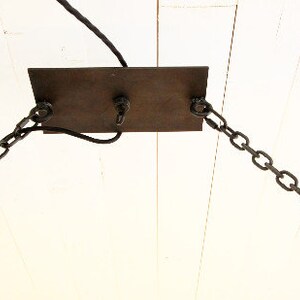 May include: A metal ceiling plate with two chains hanging down. The plate is attached to a white ceiling.