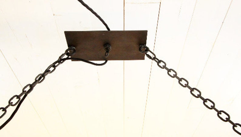 May include: A metal ceiling plate with two chains hanging down. The plate is attached to a white ceiling.