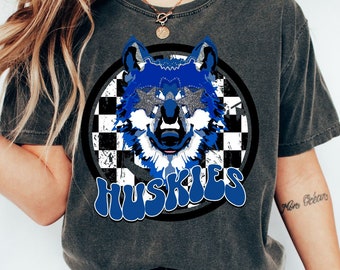 May include: A dark gray t-shirt with a blue wolf wearing sunglasses and a checkered background. The text "HUSKIES" is written in blue letters below the wolf.