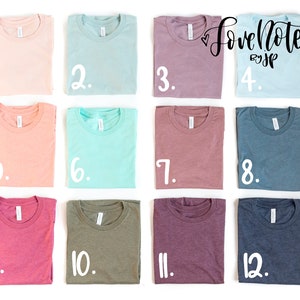 May include: Twelve folded t-shirts in various colors, including pink, blue, green, and purple. Each shirt is numbered 1 through 12.