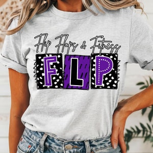 May include: A white t-shirt with the text "Flip Flops & Fitness" and the word "FLIP" in purple letters with a black outline. The letters are in boxes with a black and white polka dot pattern.
