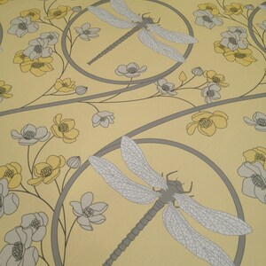 May include: A yellow background with a repeating pattern of gray dragonfly silhouettes and gray and yellow flowers. The dragonflies are in circles with a gray outline.