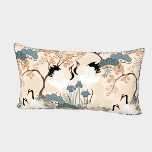 May include: A rectangular throw pillow with a cream background and a repeating pattern of white cranes, blue and green trees, and pink flowers.