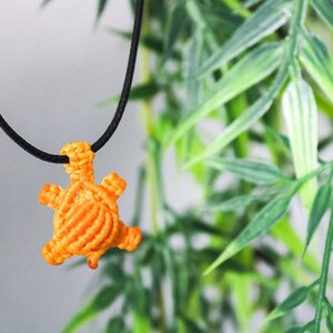 May include: Orange macrame turtle pendant on a black cord necklace.