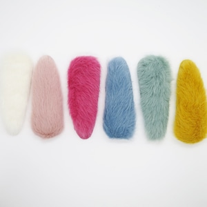 May include: Six fluffy hair clips in a variety of colours: white, pink, magenta, light blue, teal and yellow.