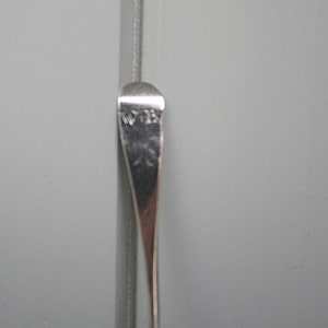 May include: Close-up of a silver spoon with the inscription "W 13" on the back.