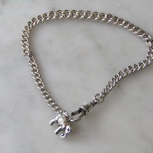 May include: A silver chain bracelet with a small silver elephant charm.