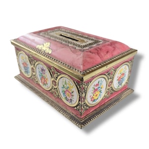 Op de afbeelding: Een rechthoekige doos in antieke stijl met een roze marmerachtige afwerking. De doos heeft ovale bloemmotieven en goudkleurige randen. Een gleuf is zichtbaar aan de bovenkant. De doos staat op een zilverkleurige basis.