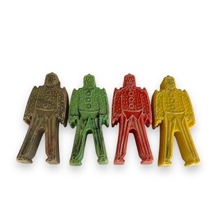 Puede incluir: Cuatro figuritas de plástico de personas en diferentes colores: verde, marrón, rojo y amarillo. Cada figurita tiene un diseño simple con una cabeza redonda, dos brazos y dos piernas.