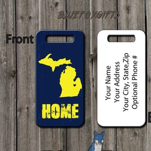 May include: A luggage tag with a blue background and a yellow outline of the state of Michigan. The word "HOME" is printed in yellow with a distressed look. The back of the tag is white with space for personalization.