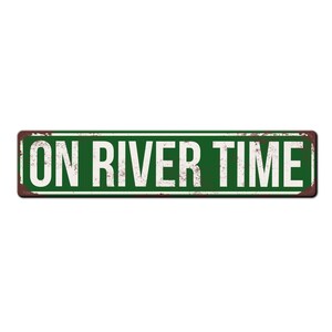May include: A green metal sign with rusty edges and white text that reads "ON RIVER TIME".