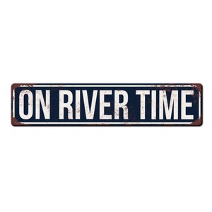May include: A blue and white metal sign with the text "ON RIVER TIME" in white letters.