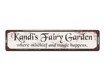 May include: A white metal sign with brown edges and a distressed look. The sign reads "Kandi's Fairy Garden where mischief and magic happens."