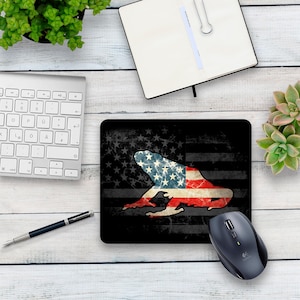 May include: A black mouse pad with a distressed American flag design and a silhouette of a frog in the center. The frog is also patterned with the American flag.
