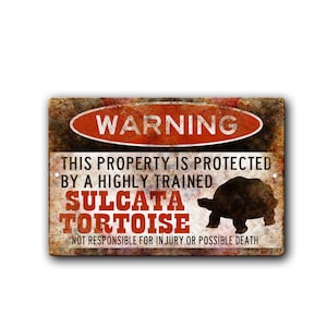May include: A rectangular metal sign with a distressed, rusty appearance. The sign features the word "WARNING" in a red oval, and text stating the property is protected by a Sulcata Tortoise. The sign also includes a silhouette of a tortoise.