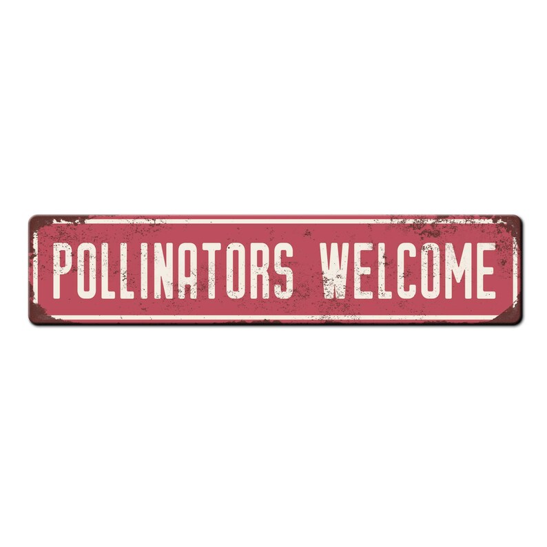 May include: A red metal sign with white text that reads "Pollinators Welcome". The sign has a distressed, rusty look.