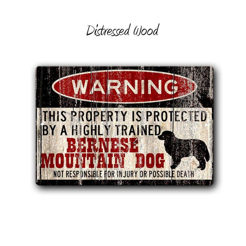 May include: A distressed wood sign with a warning sign that reads "WARNING" in red letters. The sign says "This property is protected by a highly trained Bernese Mountain Dog. Not responsible for injury or possible death." The sign features a black and white illustration of a Bernese Mountain Dog.