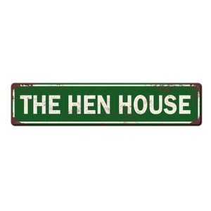 May include: A green metal sign with rusty edges and white text that reads "THE HEN HOUSE".