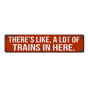 May include: A red metal sign with a distressed finish. The sign reads "There's like, a lot of trains in here."