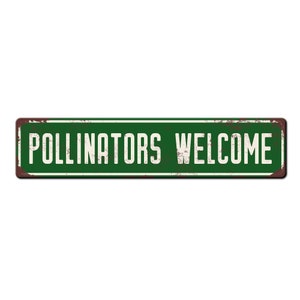 May include: A green metal sign with white text that reads "Pollinators Welcome". The sign has a distressed, rusty look.