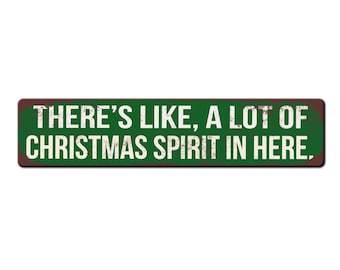 May include: A green and brown metal sign with the text "THERE'S LIKE, A LOT OF CHRISTMAS SPIRIT IN HERE."