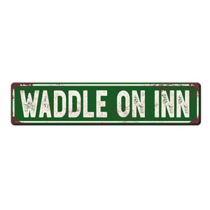 May include: A green metal sign with the text "WADDLE ON INN" in white letters. The sign has a rustic, weathered look.