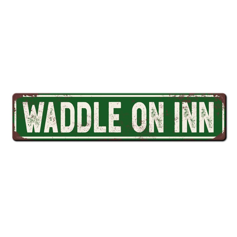May include: A green metal sign with the text "WADDLE ON INN" in white letters. The sign has a rustic, weathered look.