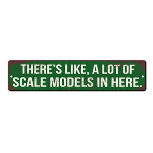 May include: A green and brown metal sign with white text that reads "There's like, a lot of scale models in here."
